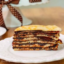 Tort unguresc de clătite în straturi, cu cremă de cacao – felie servită pe farfurie albă
