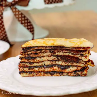 Tort unguresc de clătite în straturi, cu cremă de cacao – felie servită pe farfurie albă