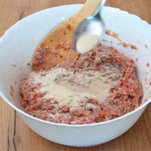 Adăugarea pesmetului în amestecul de carne tocată de pui cu legume pentru o consistență potrivită.