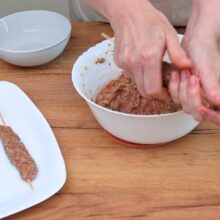 Modelarea manuală a compoziției de carne tocată de pui pe bețe din lemn, pas înainte de gătire.