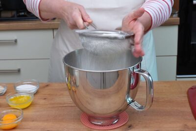 Făină cernută într-un bol mare pentru aluatul de gogoși, pas esențial pentru aerarea compoziției.