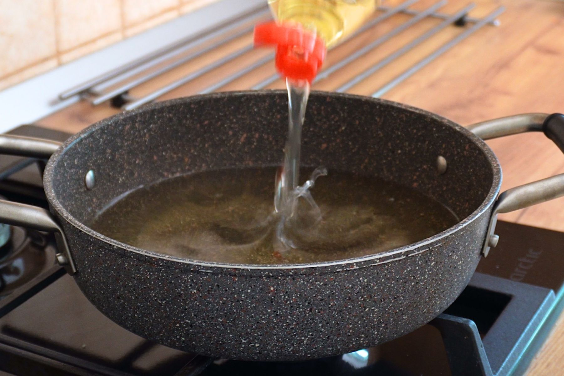 Adăugarea uleiului într-o tigaie adâncă pentru a pregăti gogoșile prin prăjire.