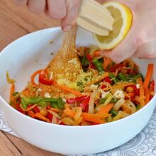 Suc de lămâie și coajă rasă adăugate peste salata caldă de năut cu legume sotate – pasul final pentru extra aromă și prospețime.