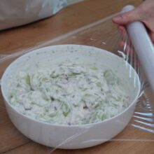bol cu salata de castraveti cu iaurt si marar acoperit cu folie alimentara pentru frigider