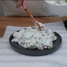 Salata de castraveți cu iaurt este transferată pe farfurie, gata pentru servire.