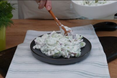Salata de castraveți cu iaurt este transferată pe farfurie, gata pentru servire.