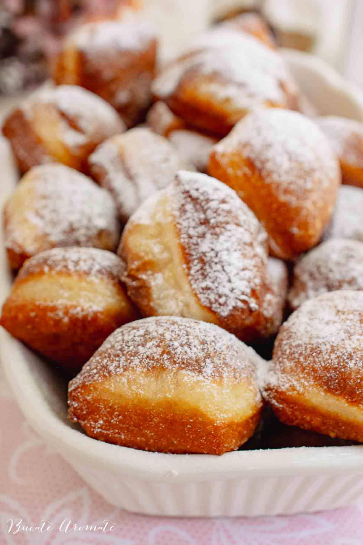 Tavă cu gogoși mari și pufoase în prim plan.