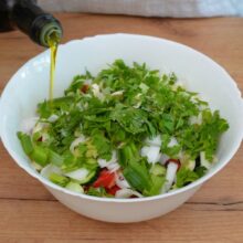 Ulei de măsline turnat peste salata țărănească cu roșii și castraveți, înainte de amestecare