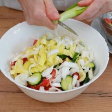 Ceapă verde tocată direct în bolul cu salată de vară, alături de roșii, castraveți și ardei gras