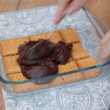 Așezați un strat de biscuiți în tavă și adăugați crema de cacao peste ei
