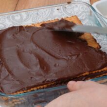 Nivelați crema de cacao peste ultimul strat de biscuiți în tava de tort