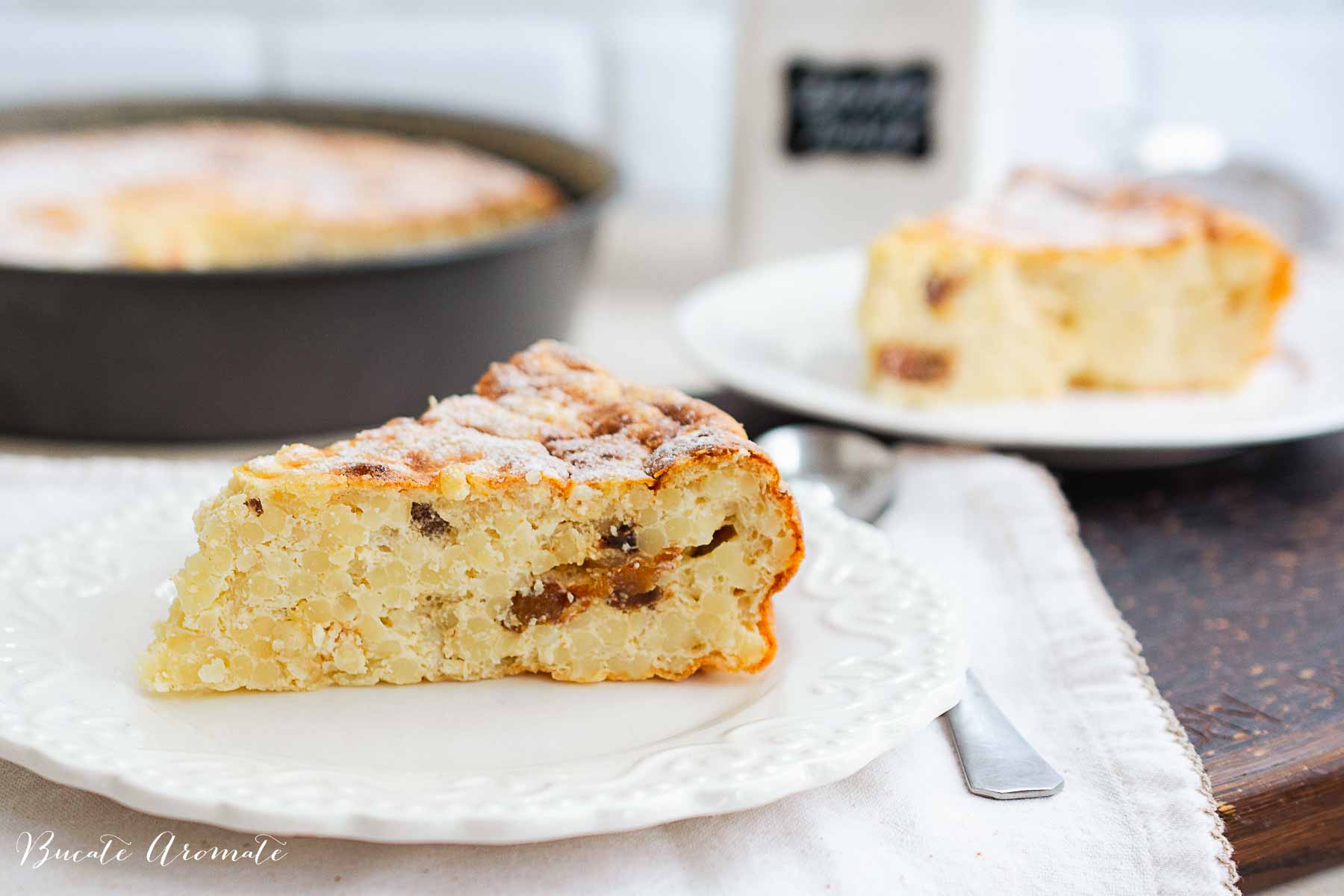 Două felii de budincă de cuscus cu brânză și stafide, cu textură pufoasă și stafide vizibile