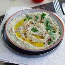 Salată de vinete cu tahini și ulei de măsline, presărată cu sumac și pătrunjel, servită într-un bol rustic.