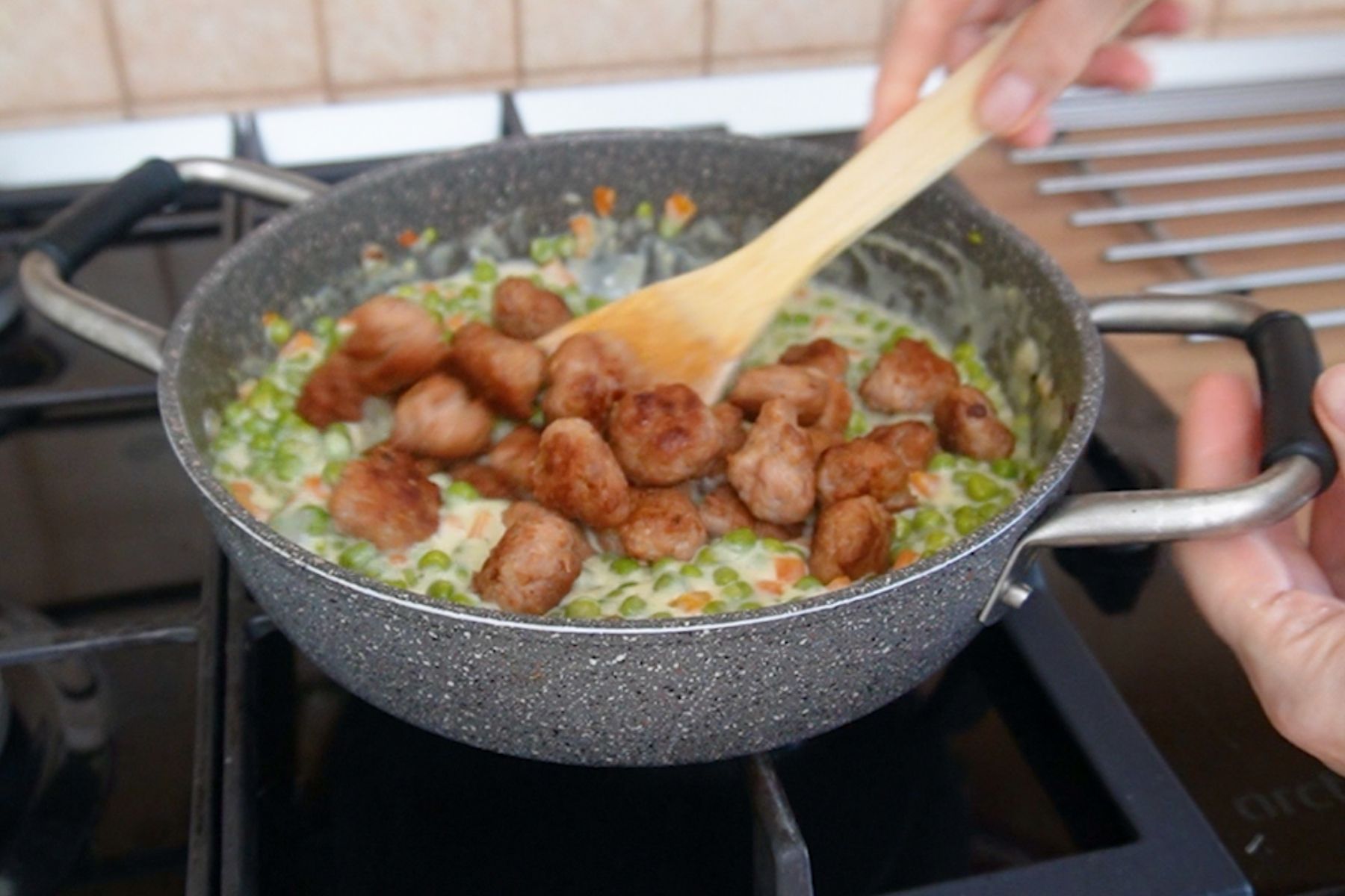 Adăugare chifteluțe prăjite în mâncarea de mazăre cu sos de smântână, pas important pentru rețeta cu chifteluțe de pui