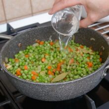 Adăugare apă peste mazăre, morcov și ceapă călită, începutul fierberii pentru mâncare de mazăre cu chifteluțe de pui