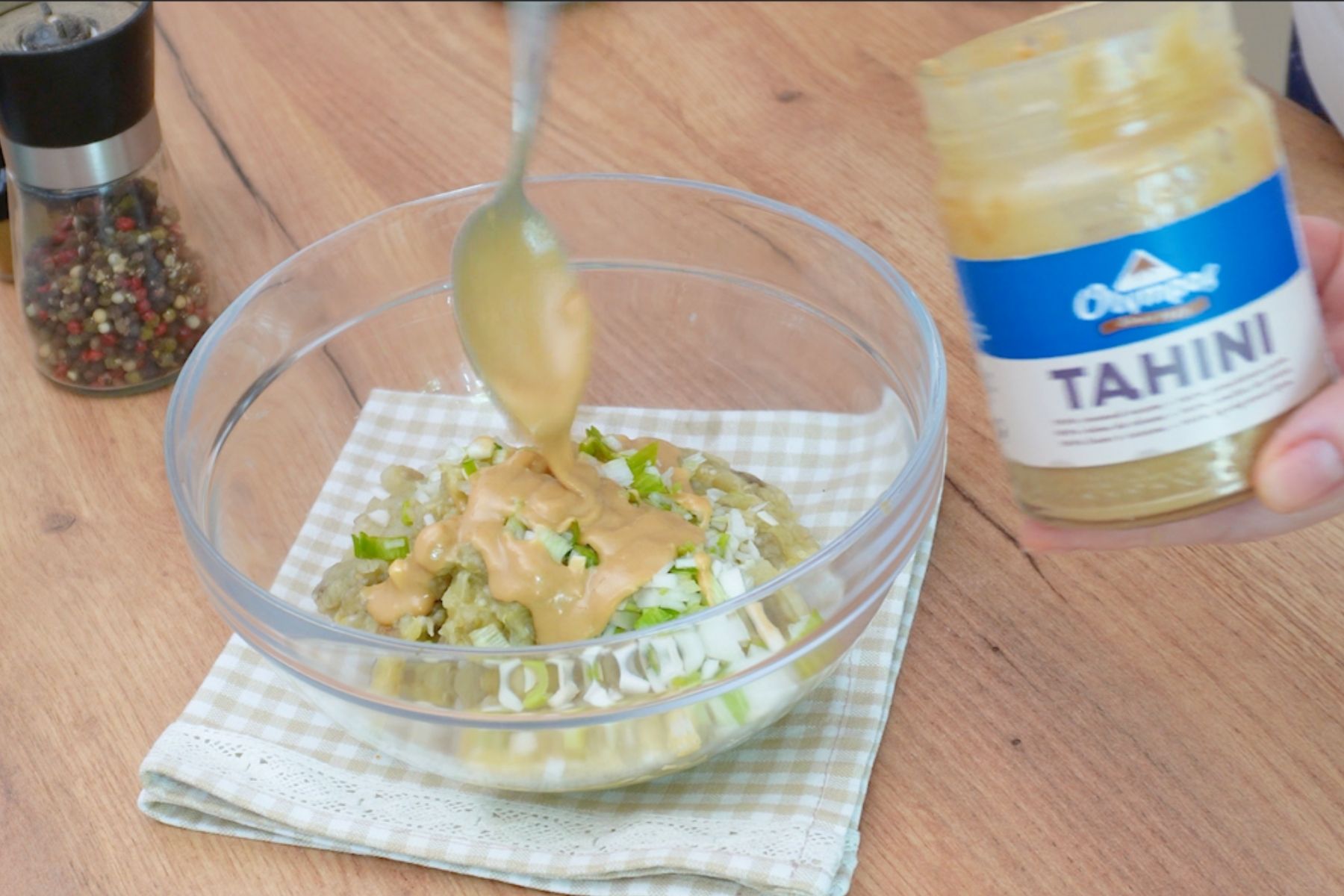 pasta de susan tahini adaugata in castron peste vinete si ceapa veede tocata pentru prepararea salatei Baba Ganoush