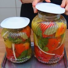 Borcane mari cu ardei umpluți cu varză și morcov, acoperite cu saramură și frunze de dafin