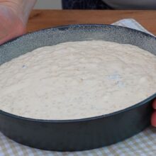 Compoziția de budincă de cuscus cu brânză turnată în tava pregătită pentru cuptor