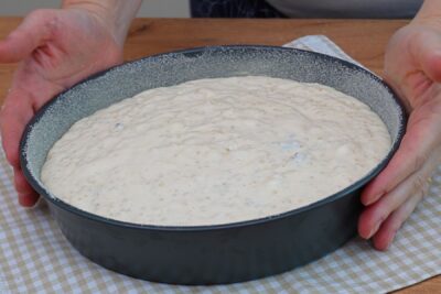 Compoziția de budincă de cuscus cu brânză turnată în tava pregătită pentru cuptor