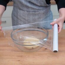 Aluat pentru covridogi pus la dospit într-un bol acoperit cu folie alimentară