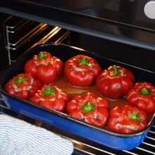 Gogoșari umpluți cu carne de pui și orez, așezați în tavă, pregătiți pentru cuptor