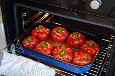 Gogoșari umpluți cu carne de pui și orez, așezați în tavă, pregătiți pentru cuptor