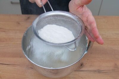 Cernerea făinii în aluatul pentru prăjitură cu iaurt și prune, pas important pentru un blat pufos