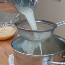 Lapte infuzat cu vanilie strecurat prin sită fină pentru crema de vanilie.