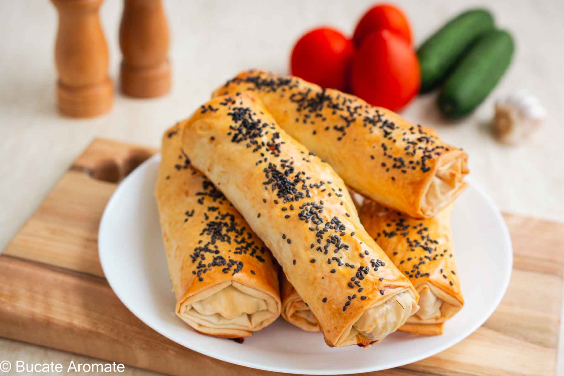 Rulouri crocante din foi de plăcintă cu umplutură de pui, cașcaval și ciuperci, servite pe farfurie albă