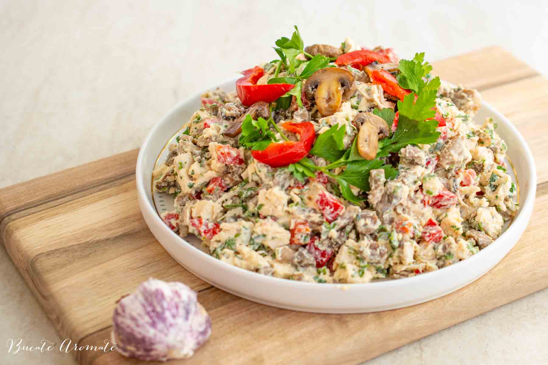 Salată cu piept de pui, ciuperci rumenite și maioneză cu usturoi, servită pe platou alb, decorată cu pătrunjel și gogoșari