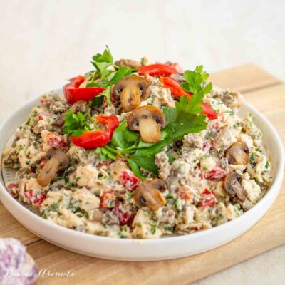 Salată ușoară cu pui, ciuperci și sos de usturoi fără ou crud, într-un bol alb pe fundal de lemn