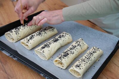 Plăcinte crude unse cu ou și presărate cu semințe, înțepate pentru a nu crăpa la copt