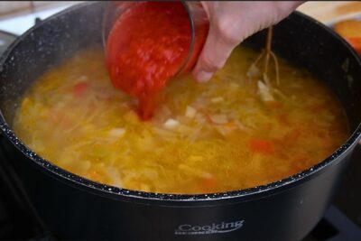 Adăugare suc gros de roșii în ciorba de varză dulce de post, pentru acrire și culoare, în rețeta tradițională cu borș.