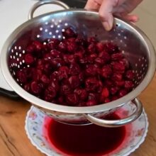 Vișine scurse în strecurătoare pentru prăjitura Cușma lui Guguță cu aluat fraged