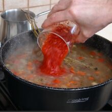 Bulion de roșii turnat peste legume și fasole în ciorba cu afumătură