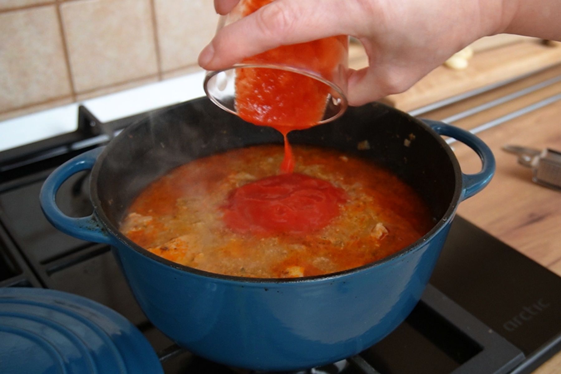 Turnare bulion gros de roșii într-o cratiță cu gulaș fierbinte, pentru sos bogat și aromat