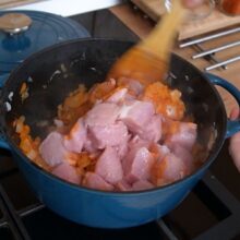 Bucăți de carne de porc în cratiță, amestecate cu ceapă călită și boia, început de gulaș tradițional