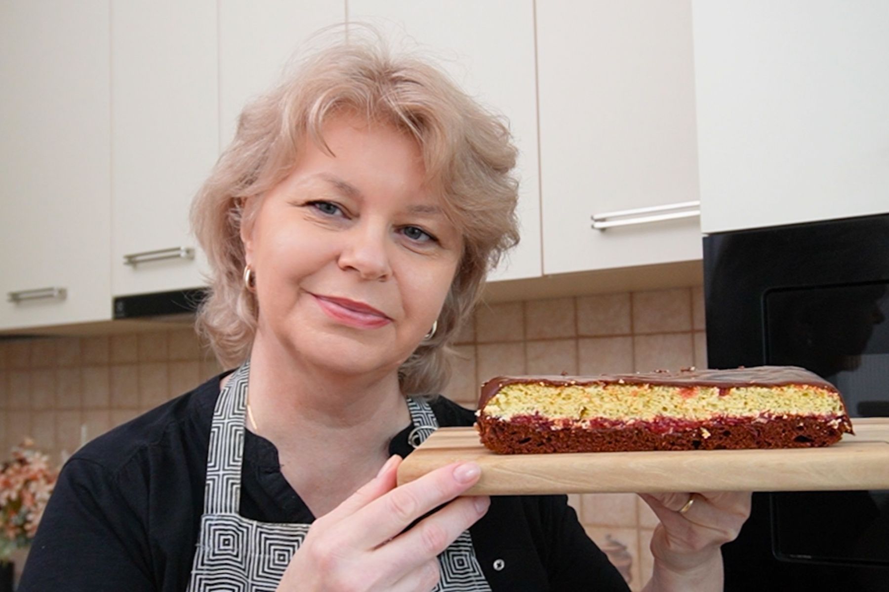 Iuliana Sbirnea ținând în  mână o tavă cu prăjitura Zi și Noapte cu gem și 2 straturi