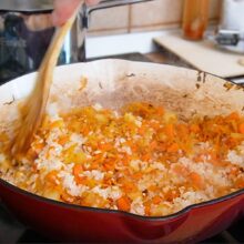 Orezul se adaugă peste ceapa călită și morcovul ras și cubulețe, în tigaie, pentru orez cu ciuperci de post la cuptor