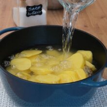 Cartofi tăiați felii, acoperiți cu apă și fierți pentru piure, într-o oală