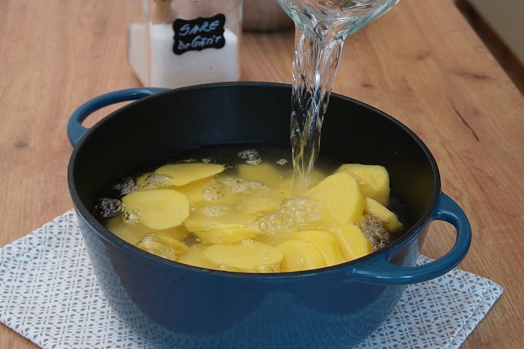 Cartofi tăiați felii, acoperiți cu apă și fierți pentru piure, într-o oală