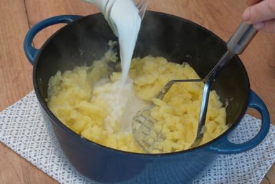 Cartofi fierți zdrobiți cu presă, peste care se adaugă lapte pentru piure cremos