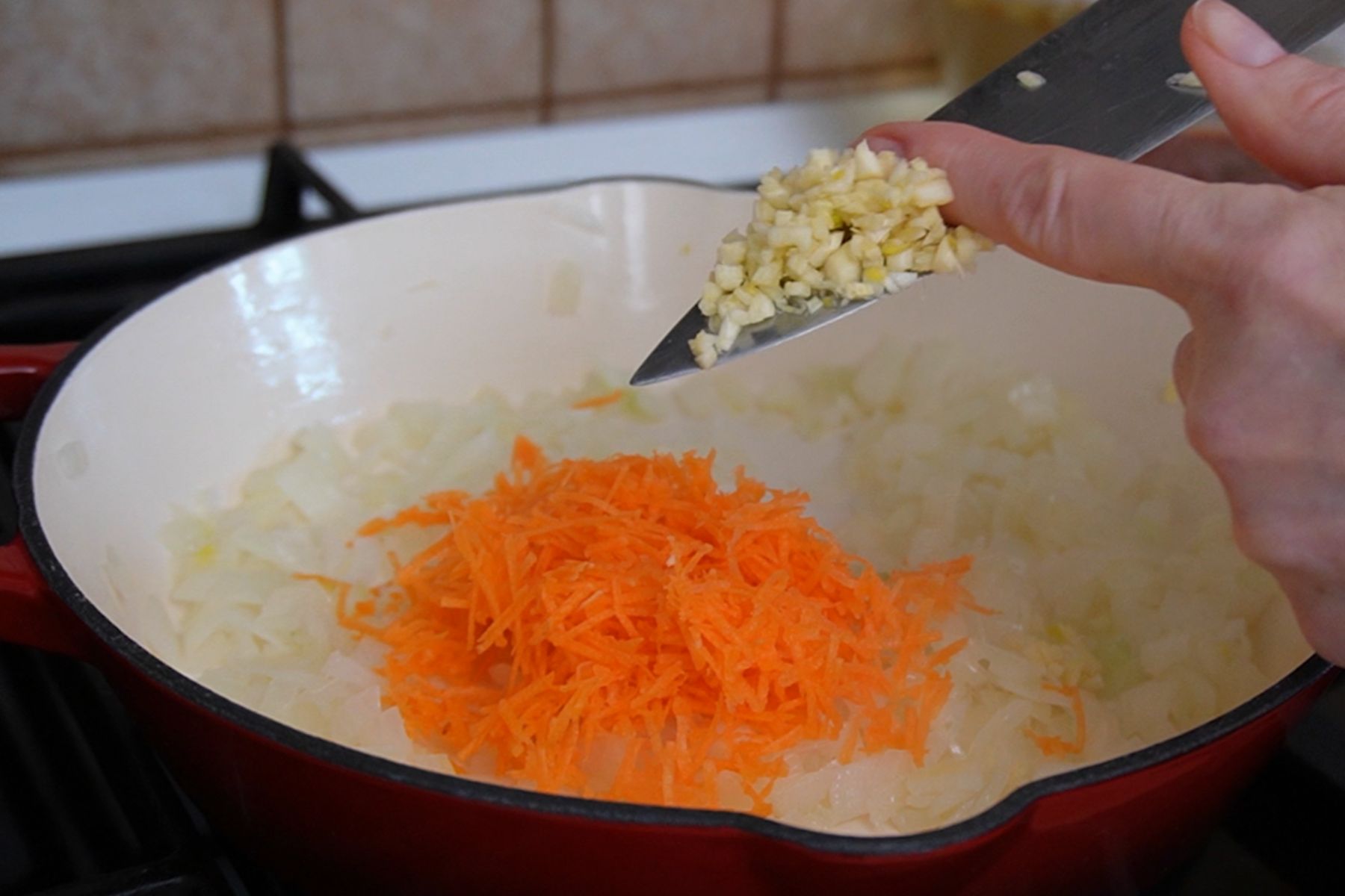 Ceapă călită cu morcov ras și usturoi adăugat în tigaie