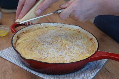 Parmezan ras fin presărat peste piure și pesmet, pentru crustă crocantă