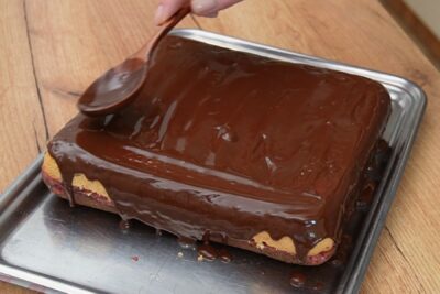 Glazură de ciocolată turnată peste prăjitura Zi și Noapte cu gem