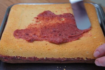 Întinderea gemului de prune între cele două blaturi ale prăjiturii Zi și Noapte