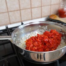 Adăugarea ardeilor copți tocați peste ceapa călită pentru zacuscă de post rapidă