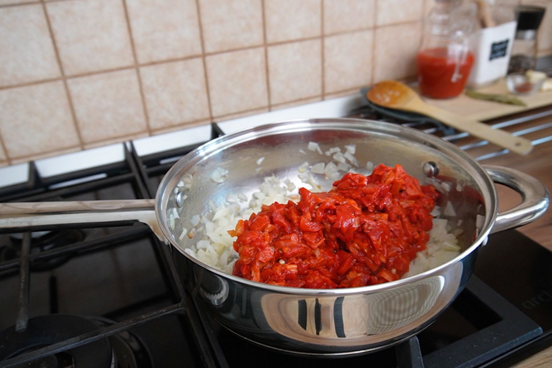 Adăugarea ardeilor copți tocați peste ceapa călită pentru zacuscă de post rapidă