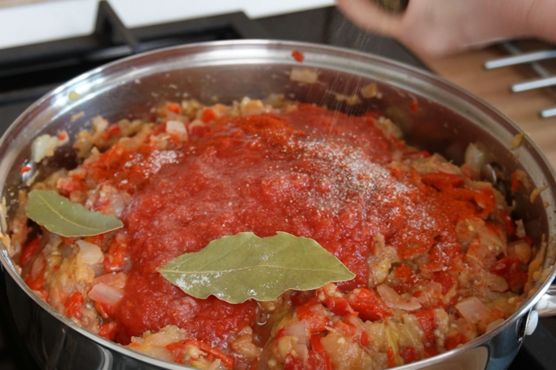 Suc de roșii, foi de dafin și condimente adăugate în zacusca de vinete și ardei copți