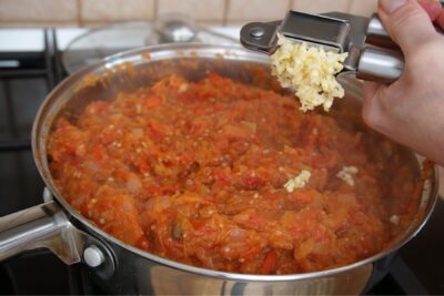 Usturoi proaspăt adăugat la final în zacusca rapidă de vinete și ardei copți